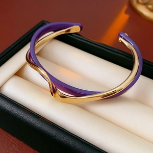 Detail of gold-plated double-layer geometric cuff with purple resin wavy band
