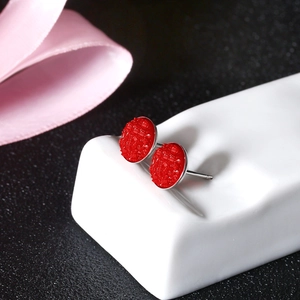 Detailed macro shot of round red crystal stud earrings on a white ceramic stand