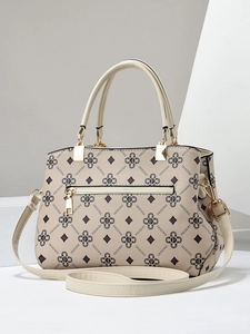 Detail of beige PU leather tote featuring brown monogram pattern and golden hardware accents