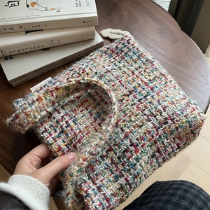Colorful hand-woven shoulder bag with thick knit texture on a wooden table setup