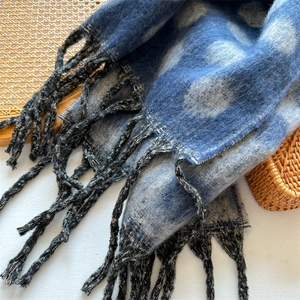 Close-up of blue and white polka dot scarf featuring soft fabric and black fringe tassels