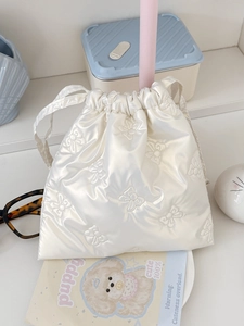 Detail of cream drawstring pouch with quilted shiny fabric and bow tie decoration