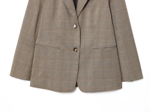 Détail de la fermeture à deux boutons et du motif à carreaux marron classique du blazer