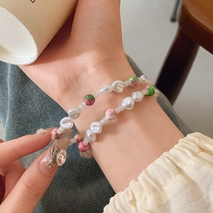Detailed view of layered beaded bracelets with irregular pearls and floral beads on wrist