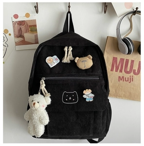 Detalle de mochila de pana negra con bordado de gato y un lindo colgante de oso de peluche