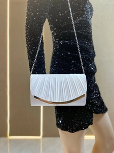 Detail of elegant pleated satin evening clutch with gold metal trim and chain strap