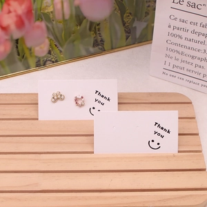 Detail of floral pearl earrings on Thank You card displayed on a wooden stand with tulips