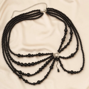 Macro detail of multilayer black bead body chain with fringe and silver lobster clasp