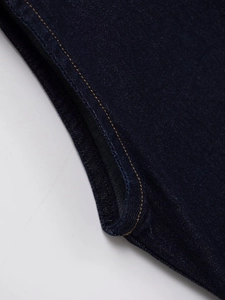 Detailed close-up of dark indigo denim fabric with contrasting yellow stitching