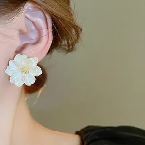 Elegant white camellia flower stud earrings with gold center and pearl resin finish
