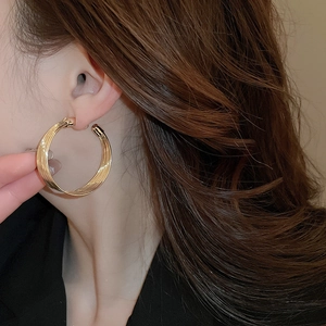 Close-up of golden multi-layer circular earrings on model with high metallic luster