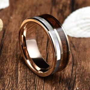 Detail of rose gold stainless steel ring with wood and mother of pearl inlay on wood