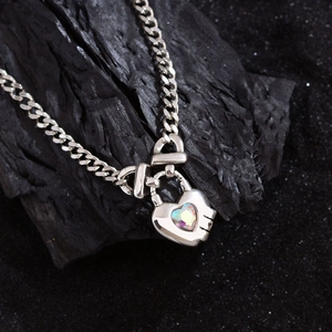 Chic silver heart lock necklace with iridescent gemstone on black stone background