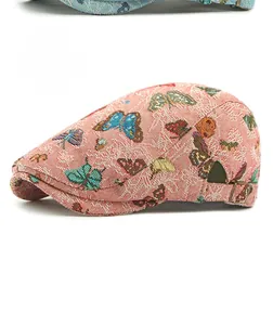 Detail of pink flat cap featuring colorful jacquard butterfly patterns and metal buckle
