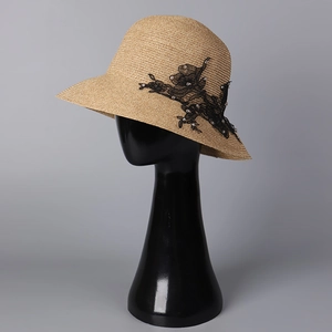 Close-up of straw sun hat featuring elegant black lace floral patterns and delicate white pearls