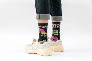 Detail of black crew socks with colorful floral patterns and text slogan on a model