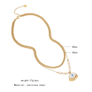 Double-layered stainless steel necklace detail with pearls and evil eye pendant charm