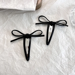 Gros plan d'une paire de barrettes papillon en cuir noir au design élégant et minimaliste