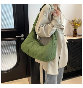 Détail du sac croissant en nylon vert matelassé avec des plis et une bandoulière