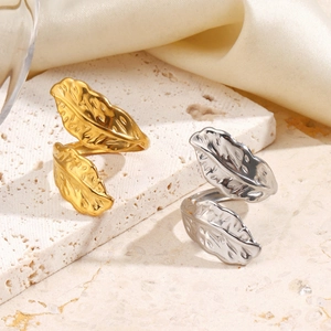 Exaggerated feather rings in gold and silver finish on stone and silk background