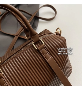 Detailed close-up of dark brown pleated leather texture and gold zipper on handbag