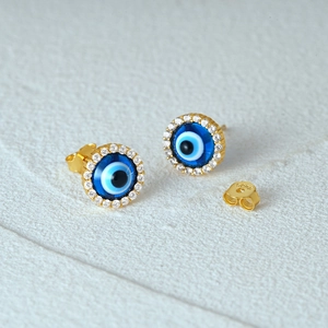 Detailed macro view of gold s925 silver evil eye stud earrings with blue zirconia inlay