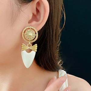 Detail of vintage bow heart earring with crystals on a model against black background