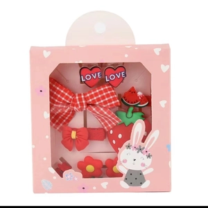 Detail von roten Haarklammern mit Erdbeer- und Herzmustern in einer rosa Geschenkbox