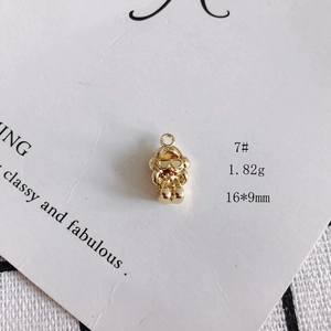 Macro view of a 16x9mm golden alloy hollow robot pendant on white textured paper