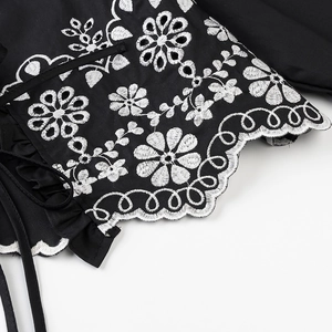 Elegant black embroidered blouse with white floral patterns and scalloped edge detail
