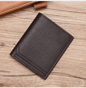 Detailed view of dark brown leather wallet with lychee texture on wooden surface