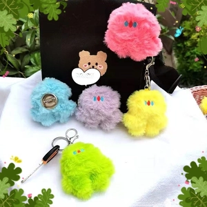 Close-up of colorful plush monster charms in pink, purple, and blue with soft textures