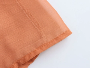 Close-up detail of the orange chiffon fabric showing the weaving texture and fine stitching
