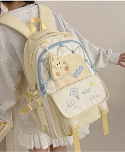 Detailed back view of a yellow school backpack with mushroom charm and happy embroidery
