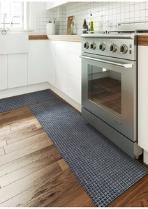Close-up of non-slip kitchen floor mats with waffle texture on dark wood floor