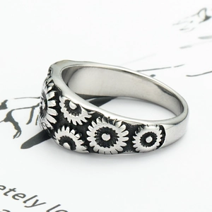 Detail view of retro stainless steel ring with engraved sunflower patterns and silver finish