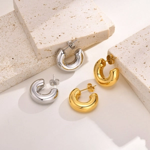 Macro detail of gold and silver chunky hoop earrings on a light textured stone surface