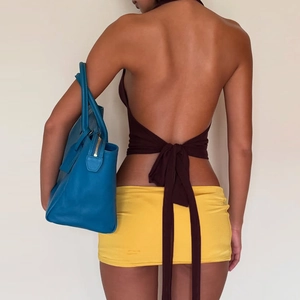 Détail du haut dos nu à lacets avec mini-jupe jaune et sac à main en cuir bleu élégant