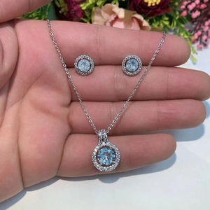 Detailed view of silver jewelry set with light blue round zircon pendants and stud earrings