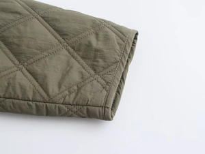 Macro view of army green diamond-quilted jacket cuff showing detailed nylon texture
