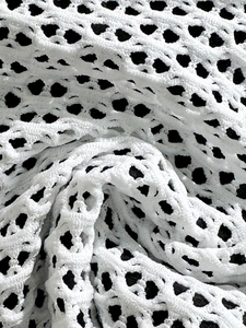 Macro detail of white mesh knit crochet fabric with textured hollow structure