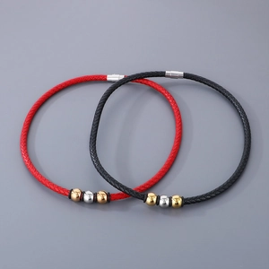 Close-up of black and red braided leather bracelets with gold and silver magnetic beads