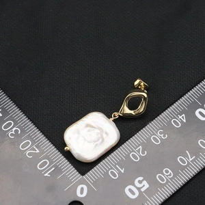 Baroque pearl drop earring with gold clasp shown on a black background with measurement scale