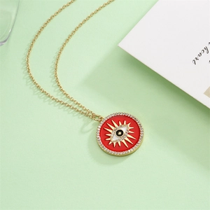 Detail of gold evil eye pendant necklace with red enamel and sparkling zircon accents