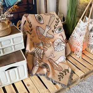 Detail of woven camping blanket with mushroom patterns and bohemian fringe trim