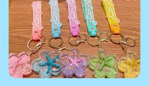 Detail of five colorful acrylic ocean star keychains with floating glitter on wood background