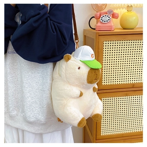 Detail of cute plush capybara backpack with green cap worn by a model in a cozy setting