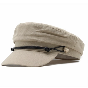 Detail of khaki newsboy hat with textured fabric, black rope trim, and gold button accents