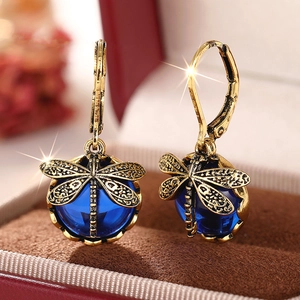 Makroaufnahme von Vintage-Libellenohrringen mit blauen Kristallen auf Samt