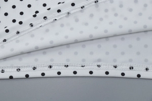 Close-up detail of white fabric with black polka dots and high-quality double stitching